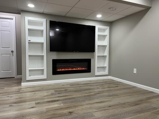 Finished Living Room with wall-mounted TV, electric fireplace and built-in shelves